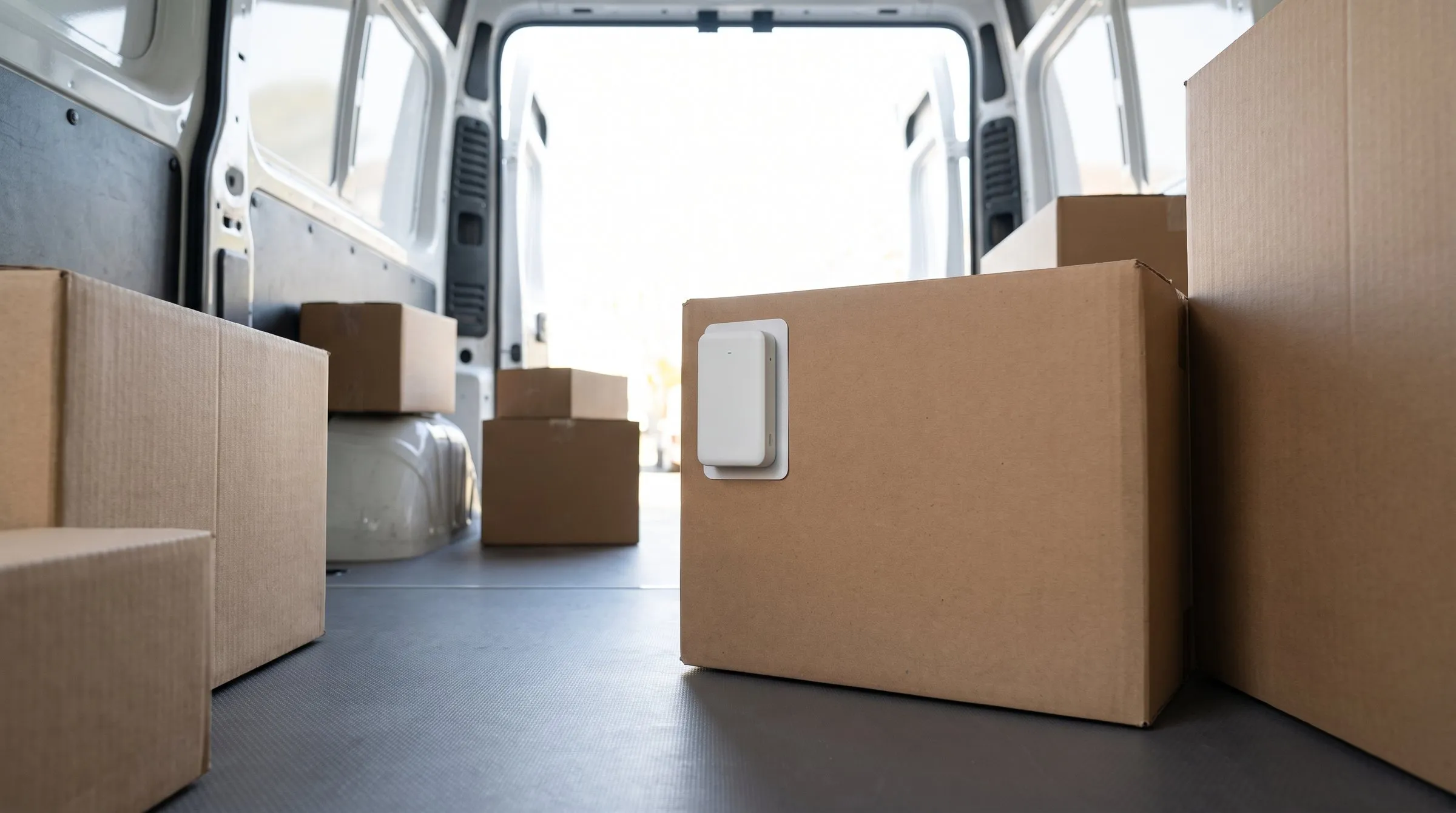 Geöffneter Laderaum eines Transporters mit Kartons, an einem Karton klebt eine weiße Bluetooth-Marke.